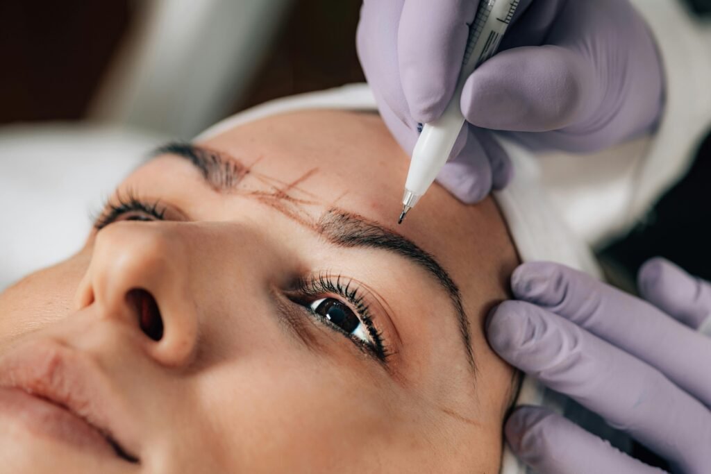 A beautician performs precise microblading on a client's eyebrows in a salon.